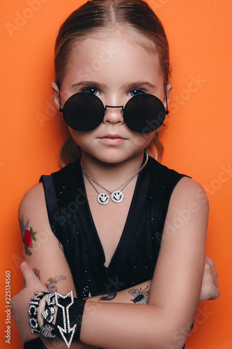 Fashion young model on an orange background, fashion kis in a black sunglasses, fashion portrait
