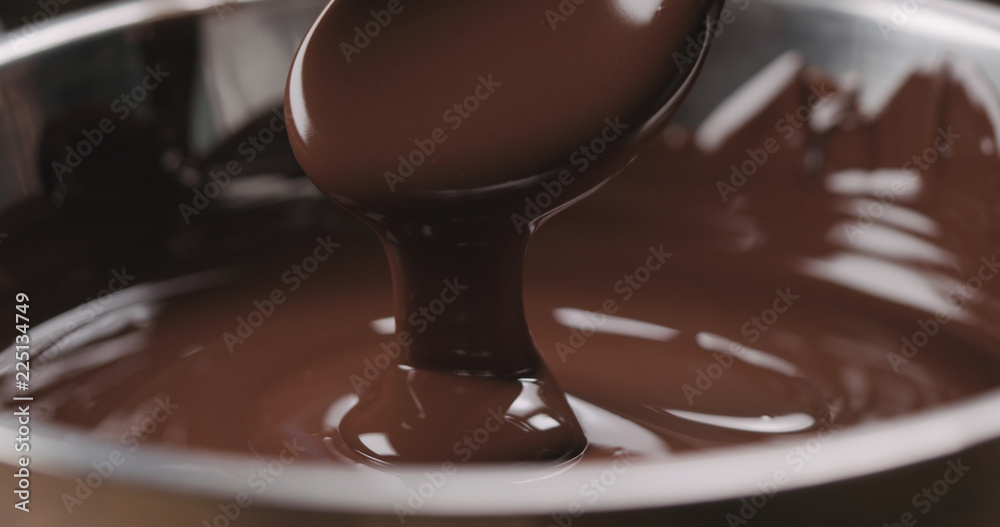 closeup pouring melted dark chocolate from spoon closeup pouring melted dark chocolate from spoon