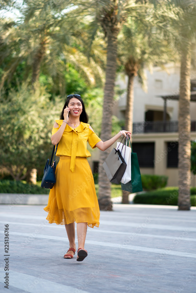 Fototapeta premium Asian girl on the phone with shopping bags