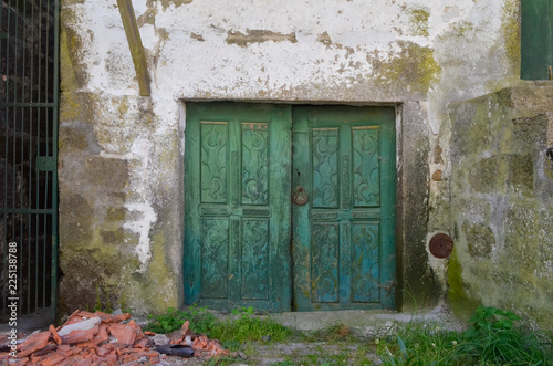 Puerta vieja de madera pintada de verde en pared de piedra encalada en Pitoes das Junias, Montalegre. Norte de Portugal. photo