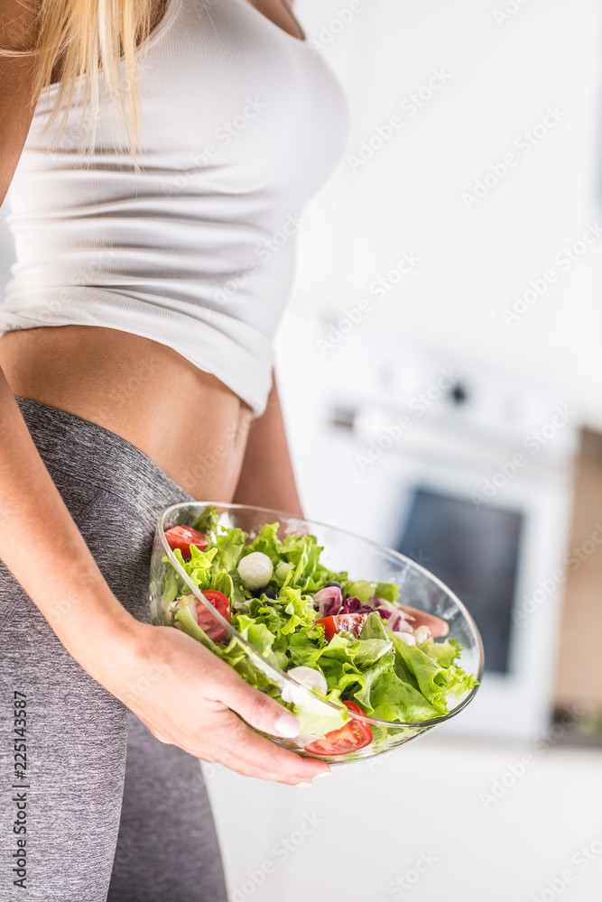Woman holding bowl with fresh vegetable salad.