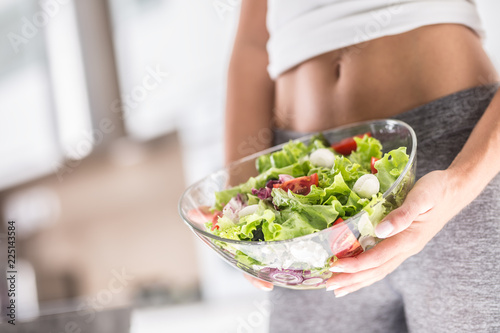 Woman holding bowl with fresh vegetable salad.