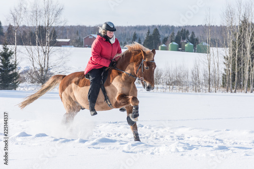 Woman on a galloping horse during winter.