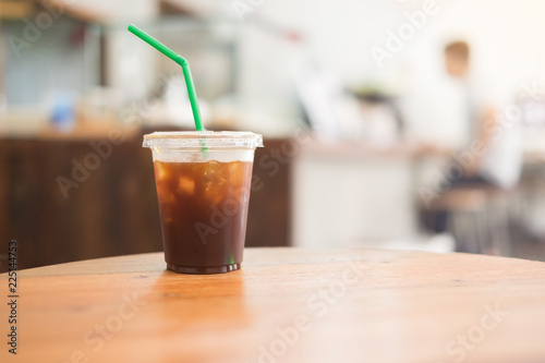 Ice coffee americano in a glass on wood table with blur interior cafe background