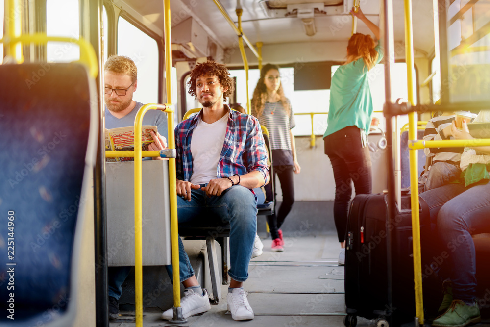 Picture of people sitting and standing in a bus. Stock Photo Adobe Stock