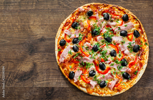 Pizza with Mozzarella cheese, ham, pepper, meat, Tomatoes, olives, Spices and Fresh Basil. Italian pizza on wooden background