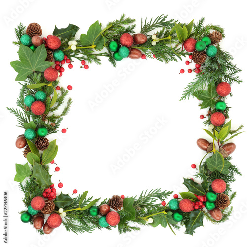 Abstract Christmas and winter square wreath garland with fir leaf sprigs, holly berries, ivy, mistletoe, bauble decorations, laurel, pine cones and acorns on white background with copy space.