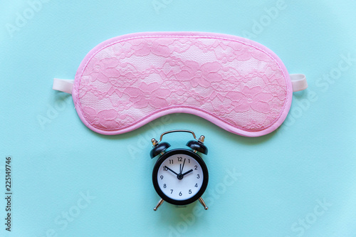 Sleeping eye mask, alarm clock isolated on blue pastel colourful trendy background. Do not disturb me, let me sleep. Rest, good night, siesta, insomnia, relaxation, tired, travel concept