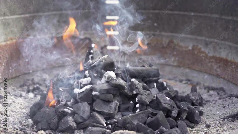 Black charcoal burning with smoke and fire in a barbecue grill in slow motion. Delicious meal preparation. Black charcoal burning with smoke and fire in a barbecue grill in slow motion. Delicious meal preparation.