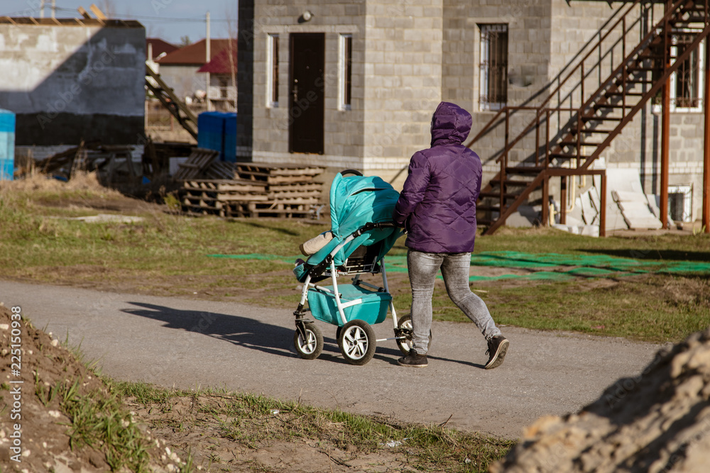 A girl with a stroller is walking along the road