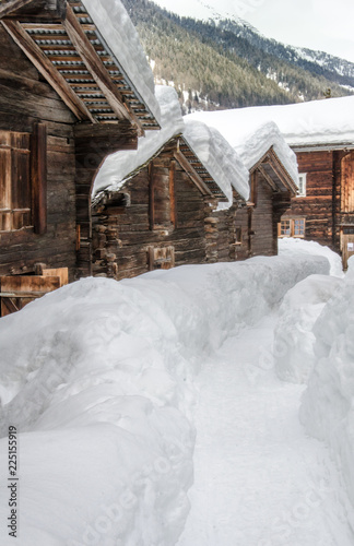 Snow covered old houses made of wood in alpine valley in Switzerland, Europe