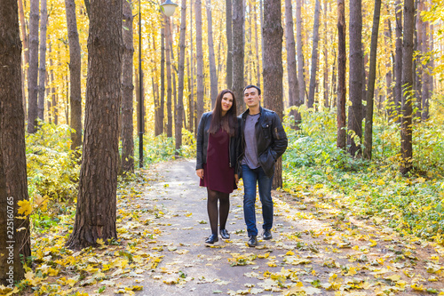 People  family and leisure concept - young couple walking in the autumn park