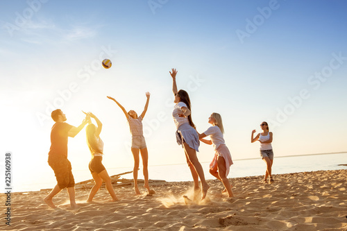 Group of friends plays ball sunset beach