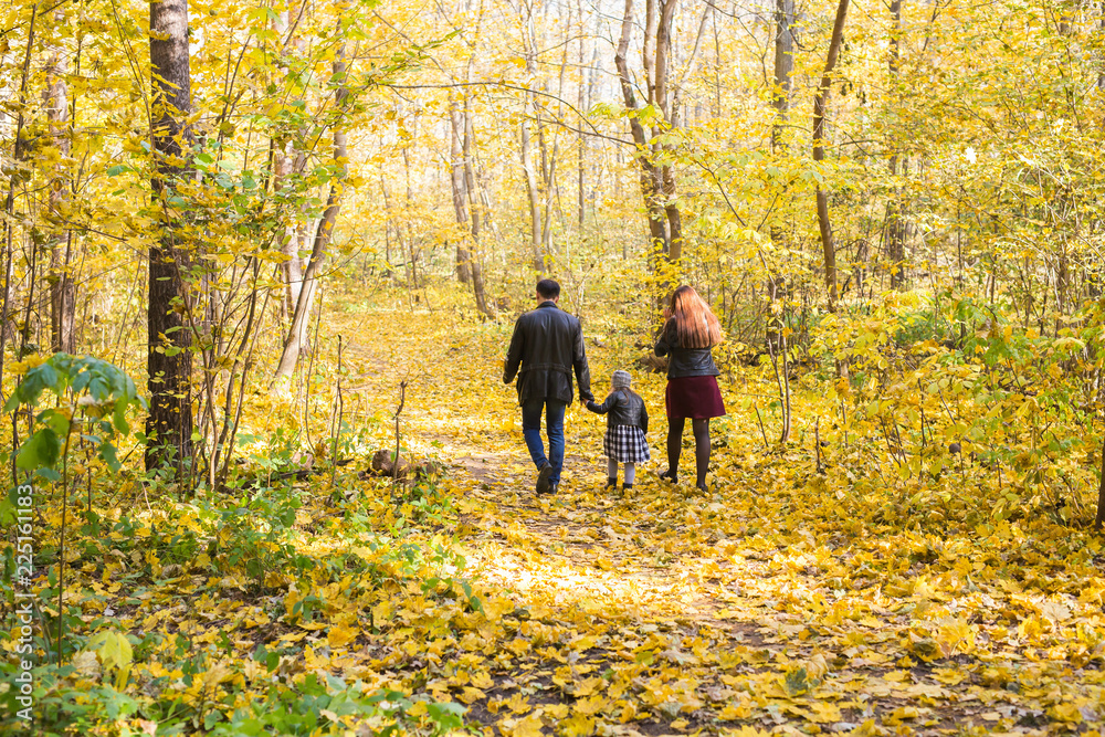 Family, autumn, people concept - young family walking in park on in autumn day, rear view Family, autumn, people concept - young family walking in park on in autumn day, rear view