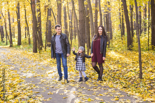 Family, autumn, people concept - young family walking in park on in autumn day