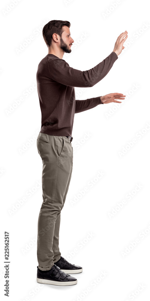 Photos A bearded man in casual clothes stands still in a side view and used both hands to touch invisible digital screen