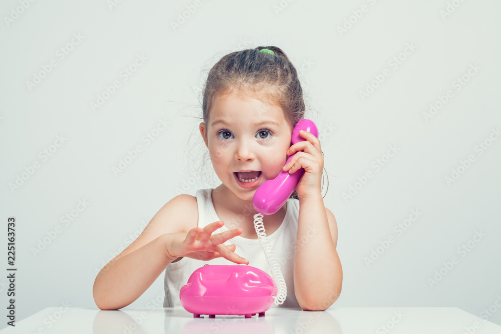 beautiful cute little girl talking on toy telephone with excited expression beautiful cute little girl talking on toy telephone with excited expression