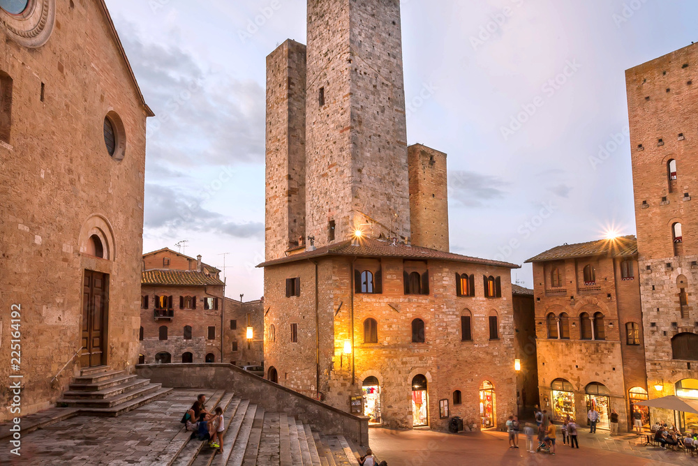 Evening with relaxing people under brick towers of ancient town of Tuscany