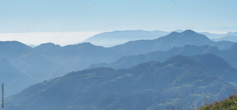 Naklejka premium Landscape on hills and Alps mountains with humidity in the air and pollution. Panorama from Farno Mountain, Bergamo, Italy