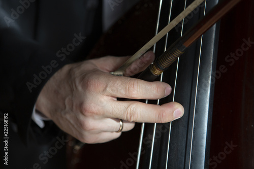 Hands of a musician playing on a contrabass closeup