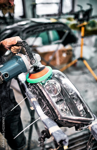  Polishing the headlights on car with the help of power tools for maintenance.