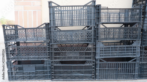 Cajas de plástico vacías negras usadas para  almacenaje de frutas, vegetales y otros alimentos apiladas o almacenadas para reciclaje
