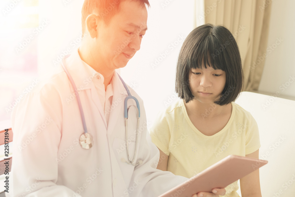 Professional kind general medical pediatrician doctor in white uniform gown with stethoscope consult with Asia child patient with modern technology tablet in hospital Professional kind general medical pediatrician doctor in white uniform gown with stethoscope consult with Asia child patient with modern technology tablet in hospital