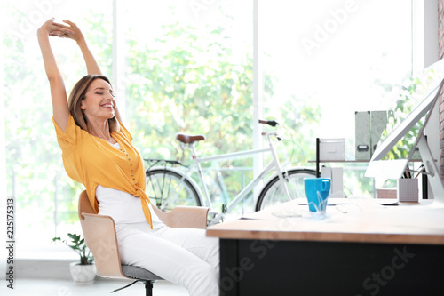 Beautiful young businesswoman stretching in office. Workplace fitness