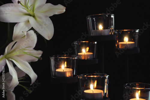Fototapeta Naklejka Na Ścianę i Meble -  Burning candles and flowers on dark background. Funeral symbol