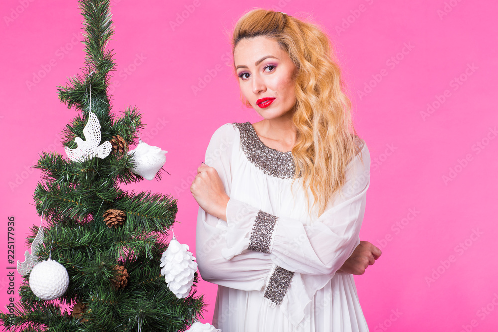 Holidays concept - Blonde woman near christmas tree on pink background