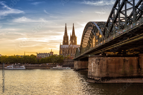 A view of Cologne Cathedral across the Rhine river at sunset.