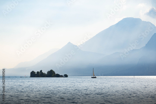 sailingboat approaching the island of Trimelone in Lake Garda Italy in a misty evenig light