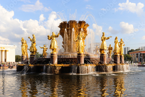 Summer fountain with gold sculptures. Blue sky with white clouds.