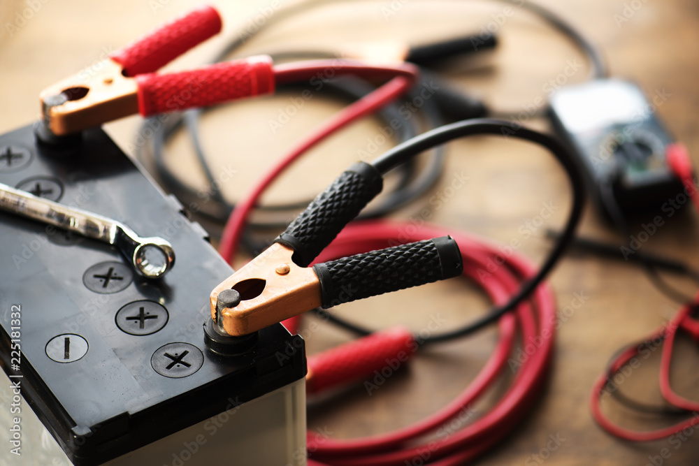 A Car battery with red and black battery Jumper Cables with copper clamps  attached to the terminals. Stock Photo | Adobe Stock