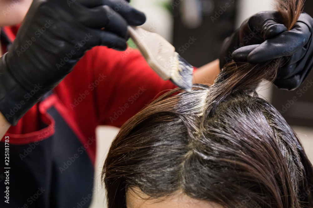 Naklejka premium Closeup of hair dresser applying chemical color dye onto hair