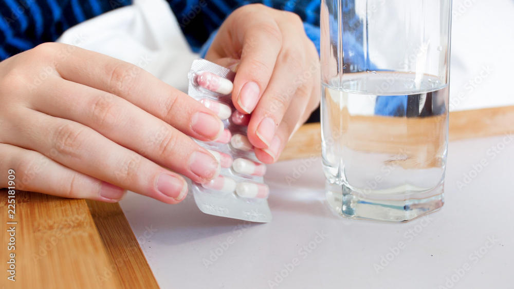 CLoseup image of female hands unpaking pills