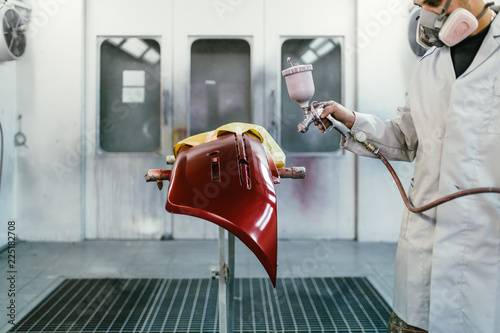 Canvas Print Man with protective clothes and mask painting car parts using spray compressor