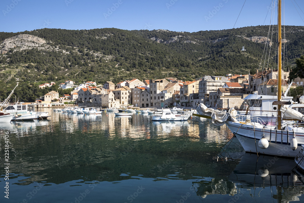 Fisherman's boats and old stone houses in port of Komiza on island Vis in Croatia