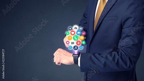 Businessman wearing smartwatch with colored application symbols on it.
