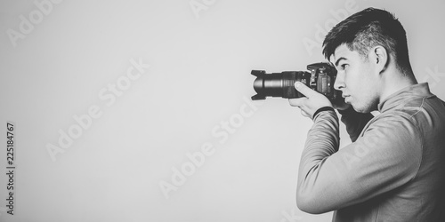 Profile portrait of young photographer with camera. Monochrome image with copy space.