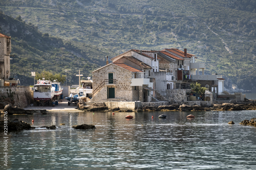Fisherman's boats and old stone houses in port of Komiza on island Vis in Croatia Fisherman's boats and old stone houses in port of Komiza on island Vis in Croatia