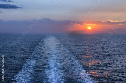 Sea horizon at sunset with ship wake. Visible trail  wake or path of a ship during the sundown. Romantic traveling evening.