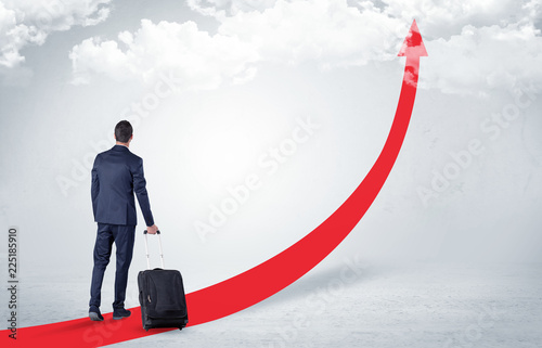 Young businessman with back leaving on the red arrow carpet to the skies with luggage on his hand  