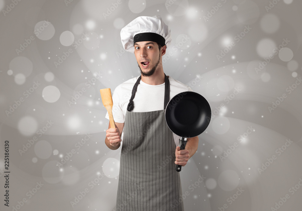 Male cook with kitchen tools and shiny grey wallpaper
Male cook with kitchen tools and shiny grey wallpaper