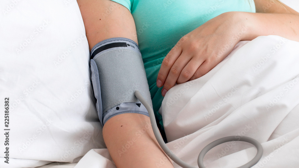 Closeup photo of female patient measuring blood pressure in hospital bed Closeup photo of female patient measuring blood pressure in hospital bed
