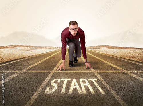 Young determined businessman kneeling before start line