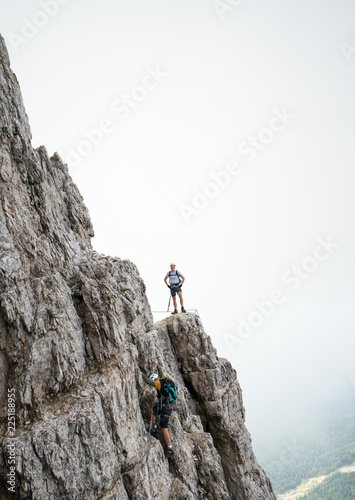 two young attractive male mountain climbers on very exposed Via Ferrata in the Dolomites of Italy