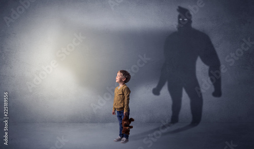 Cute kid in a room with plush on his hand and hero shadow on his background
