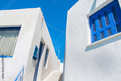 Typical traditional cycladic white houses with blue windows in the narrow streets of Milos greek islnd in Cyclades, Greece photo