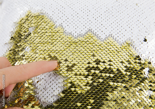 Close up view of woman finger play with gold and white shimmer sequin reversible fabric. Arts and crafts material idea concept and great stress reliever. New popular material. photo